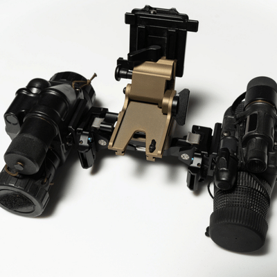 Close-up of night-vision goggle components and bridge mount displayed on white studio surface for inspection