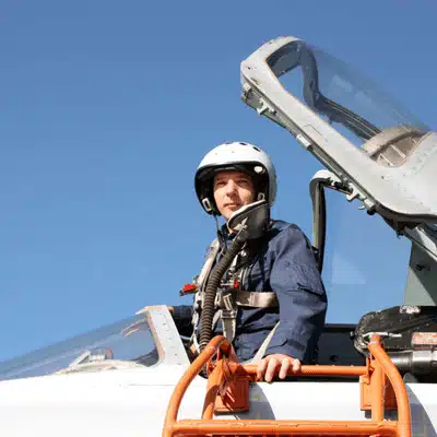 Pilot stands on ladder by open canopy, wearing helmet, showcasing nvg white phosphor readiness outside