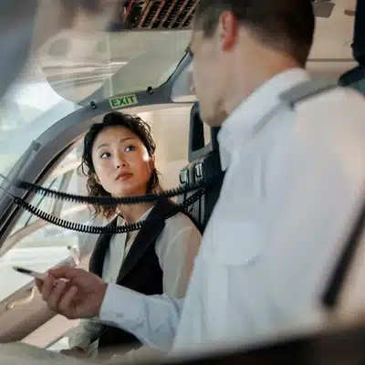 Two pilots seated in cockpit discuss procedures over intercom, reviewing checklist before helicopter flight departure