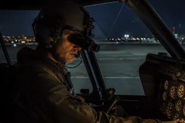 A pilot wearing night vision goggles completes cockpit checks during an NVG training course at night