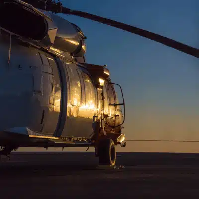 Helicopter sits on tarmac in low light, ready checks before helicopter nvg training night operations