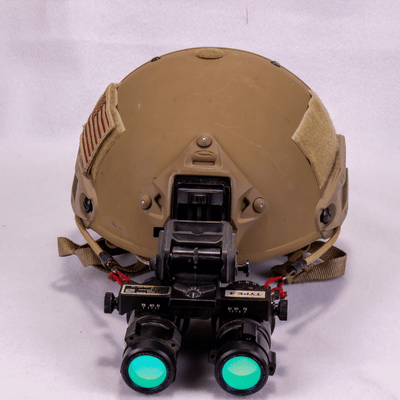 Front-facing view of helmet-mounted night vision goggles glowing green, showcasing advanced low-light optical capability