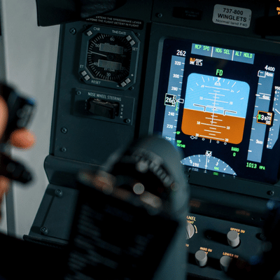 Flight director displays on modern glass cockpit screen as pilot grips controls during instrument training