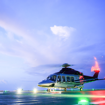 Helicopter on illuminated helipad at dusk, illustrating night vision goggle online training readiness and safety