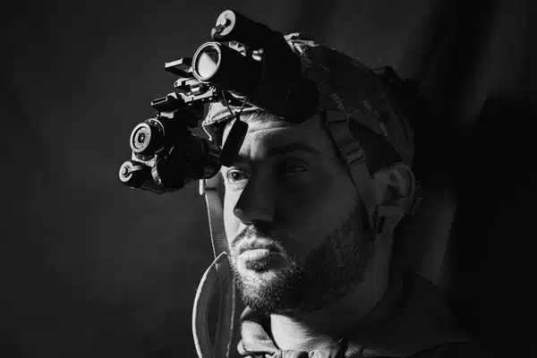 Black-and-white portrait of man wearing helmet-mounted night vision goggles, nvg white phosphor training setup indoors