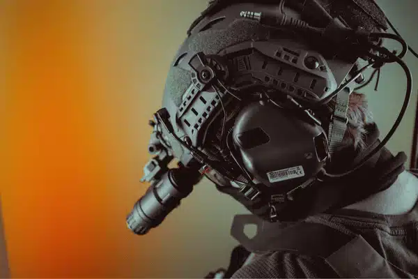 Operator wears helmet-mounted optics and headset, showing gen 3 night vision goggles in profile view