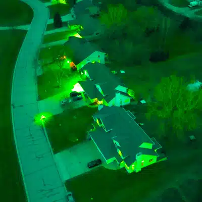Suburban homes glow under green tint captured by gen 3 night vision aerial surveillance device