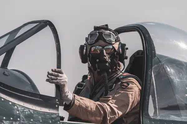 A military pilot wearing helmet and oxygen mask sits in cockpit, preparing for flight today