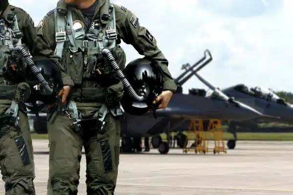 Photo shows pilots holding helmets on runway beside jet, highlighting nvg military flight readiness