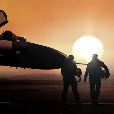 Two pilots walk beside aircraft at sunset holding helmets preparing for army nvg missions tonight