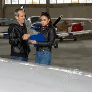 Two aviation professionals review a checklist before flying with night vision goggle-equipped aircraft