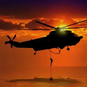 A helicopter crew conducts ocean rescue during sunset using aviation night vision goggles technology