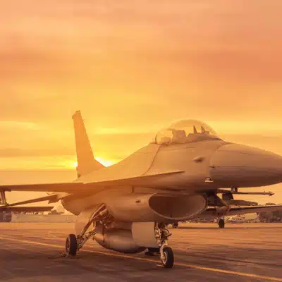 Modern fighter jet parked on tarmac at sunrise, engines off during preflight maintenance checks routine