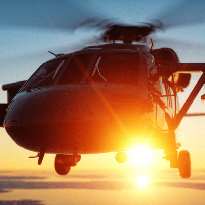 Low-flying helicopter approaches sunrise, pilots training with helicopter night vision goggles for demanding conditions safely