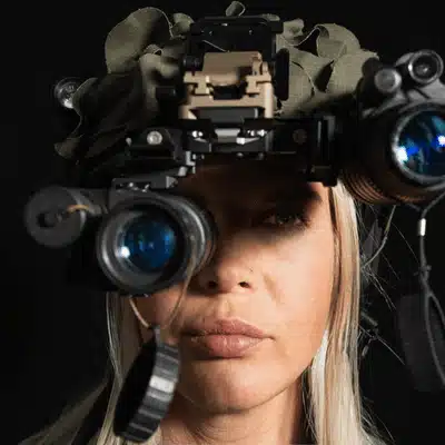 A woman wears a gen 3 night vision headset, ready for nighttime tactical or field missions
